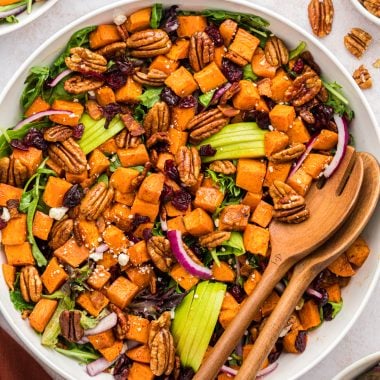 Sweet potato salad in a serving bowl made with cinnamon roasted sweet potatoes and pecans, crumbled bacon, sliced apples, Craisins, mixed greens, feta cheese, and sliced red onions. Served with a maple vinaigrette.