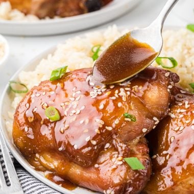 This Brown Sugar Soy Chicken has a simple marinade of brown sugar, soy sauce, butter, water, and seasoning. Part of the marinade is reserved as a glaze for the chicken after it bakes. Whether you marinate it for two or twenty-four hours, the chicken has tremendous flavor. This baked chicken is easy to prepare and is a perfect weeknight meal. Here the chicken is served on a plate with a side of rice with a spoon glazing the chicken with the reserved sauce.