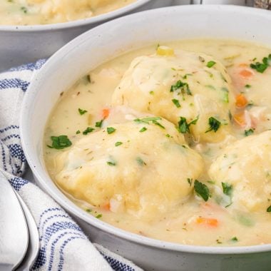 This Homemade Chicken and Dumpling soup is a flavorful, comforting soup, perfect for a rainy day or when sickness hits at home. The dumplings are like drop biscuits, they are easy to make and come together in a few minutes before cooking in the soup. My favorite thing about this soup is the delicious, thickened broth that results from the dumplings cooking in the soup. This has been a family favorite for years. Here the soup is pictured served in two soup bowls with a linen, spoons, and a spring of rosemary.