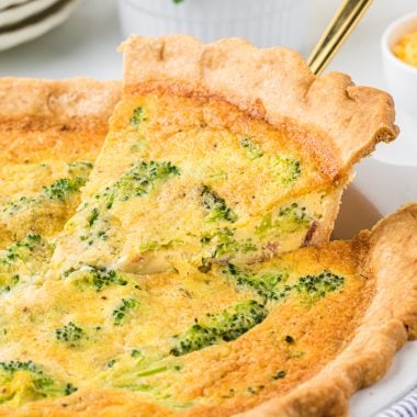 This Broccoli and Bacon Quiche is a breakfast favorite. The flaky crust, creamy custard, and bacon, broccoli, and cheddar cheese filling is rich, incredibly flavorful, and one of the best breakfast treats you can have. This is a perfect dish for a holiday brunch or a special weekend breakfast. In the picture, the quiche is pictured in the center with the first piece of the quiche being removed with a pie server and plates and juice in the background.