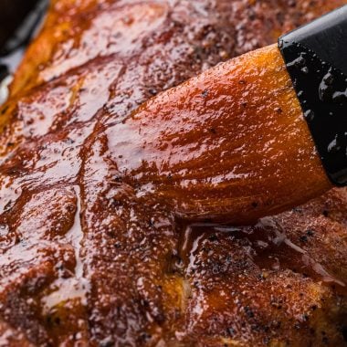 These Baby Back Barbecue Ribs have a delicious smoky rub and a sweet barbecue glaze. Baked in the oven and finished in the grill or broiler, they are tender every time and are a year-round favorite. Here the ribs are pictured just after baking in the oven in the pan with the barbecue glaze being brushed on top.