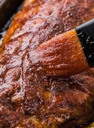 These Baby Back Barbecue Ribs have a delicious smoky rub and a sweet barbecue glaze. Baked in the oven and finished in the grill or broiler, they are tender every time and are a year-round favorite. Here the ribs are pictured just after baking in the oven in the pan with the barbecue glaze being brushed on top.