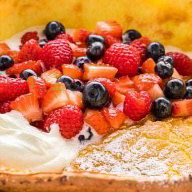 This Dutch Baby Pancake with Macerated Berries and Whipped Cream uses just a few ingredients to create an impressive, irresistible brunch classic. The oven-baked pancake puffs in the oven, creating a slightly crisp outside and a tender, custardy center. Ready in 30 minutes, they are an easy and favorite addition to weekend and holiday breakfasts. In the image, the pancake is in the skillet in the center with macerated berries and whipped cream on top.