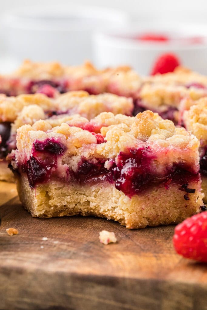 Here the Berry Crumb Bars have been cut on a cutting board and the center bar has a bite taken out of it.